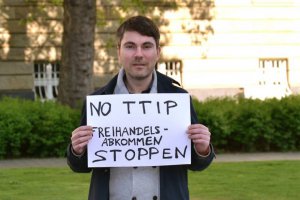 Bild von Fabio De Masi, Mitglied des Europäischen Parlaments für DIE LINKE, protestiert mit einem Schild gegen TTIP